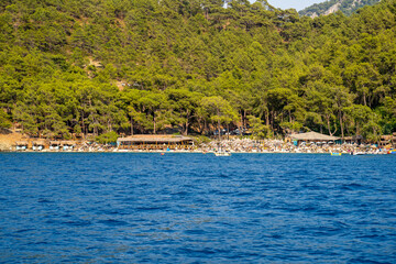 Wall Mural - Tourists swimming and sunbathing on the beach in Fethiye Bay. Mugla, Turkey - July 10, 2023.