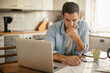 © Geber86 - Young man going over his home finances in the kitchen