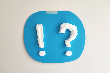 Wall Mural - question mark and exclamation mark made of cream or shaving foam on blue background