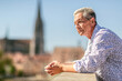 Urban lifestyle and traveling: Portrait of an elderly best ager man posing in a city at a sunny day in summer outdoors