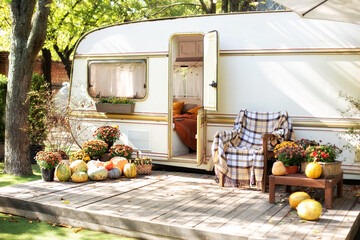 Poster - Wooden RV house porch with garden furniture. Campsite in garden. Wooden armchair near outside caravan trailer. Halloween design home. Interior cozy yard campsite with fall flowers potted and pumpkins.