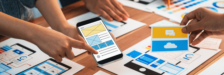 Wall Mural - panorama shot of front-end developer team brainstorming ui and ux designs for mobile app on paper wi