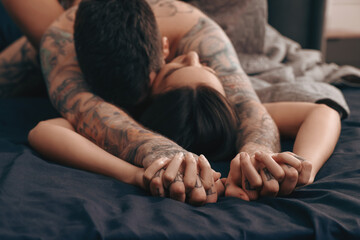 Wall Mural - passionate couple having sex on bed, focus on hands