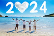 © Creativa Images - Cheerful family standing together looking at clouds shaped numbers 2024 new year numbers and heart