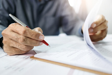 Close-up view, asian businessman reviewing before sign document reports at office workplace. legal expert, professional lawyer reading and checking financial documents or insurance contract