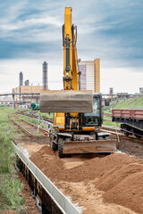 A powerful wheeled excavator prepares the site for the construction of the railway. Excavator with a wide bucket leveling the surface of the railway track. Excavation.