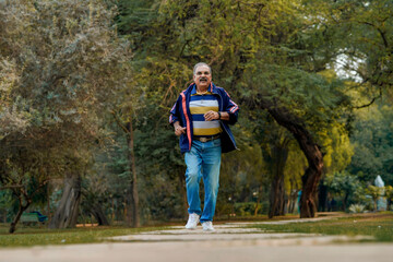 Indian old man running or jogging at park