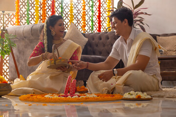 Wall Mural - South Indian couple decorating house with flower garland to celebrate Onam