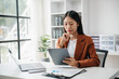 © laddawan - Business woman using tablet and laptop for doing math finance on an office desk, tax, report, accounting, statistics, and analytical research concept in office