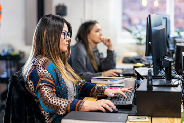 Businesswoman working on computer with colleague in background