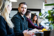 © Westend61 - Smiling businessman sitting with colleagues at desk