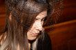 Nahaufnahme einer trauernden jungen Frau mit Trauerschleier in der Kirche (Symbolbild, model released)