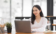 © David - Young asian woman using laptop computer for business studying, watch online virtual webinar training meeting, video call. Focused asian woman or Latin business woman work in office, copy space.