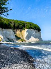 Wall Mural - Waves in sea near coastline on empty pebble beach.