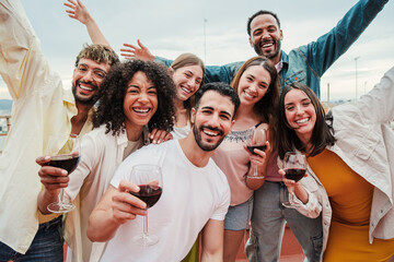 group of young adult best friends having fun toasting a red wine glasses at rooftop reunion or birth