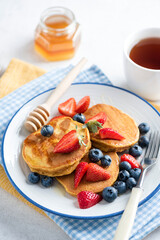 Wall Mural - Pancakes with berry fruits strawberry blueberry, cup of tea and honey. Breakfast meal