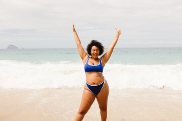 Wall Mural - Happy plus size woman in a bikini celebrating and having fun at the beach