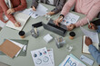 © Seventyfour - Above view of workplace with financial documents and hands of several young intercultural economists organizing work at meeting in office