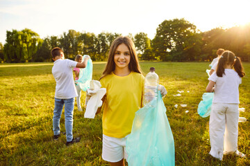 portrait of a smiling young child girl and children volunteers with gloves and garbage bags cleaning