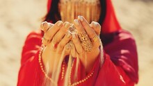 Arabian Woman Hands Touching Holding Sand Desert Beauty Face Hidden By Facekini Gold Mask Veil Chain. Luxury Lady Red Dress Silk, Dark Long Hair. Sexy Girl Arab Style Fashion Model. Nature Dubai UAE