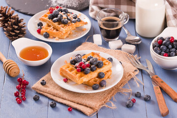 Wall Mural - Waffles with red currant and blueberries on white dish.