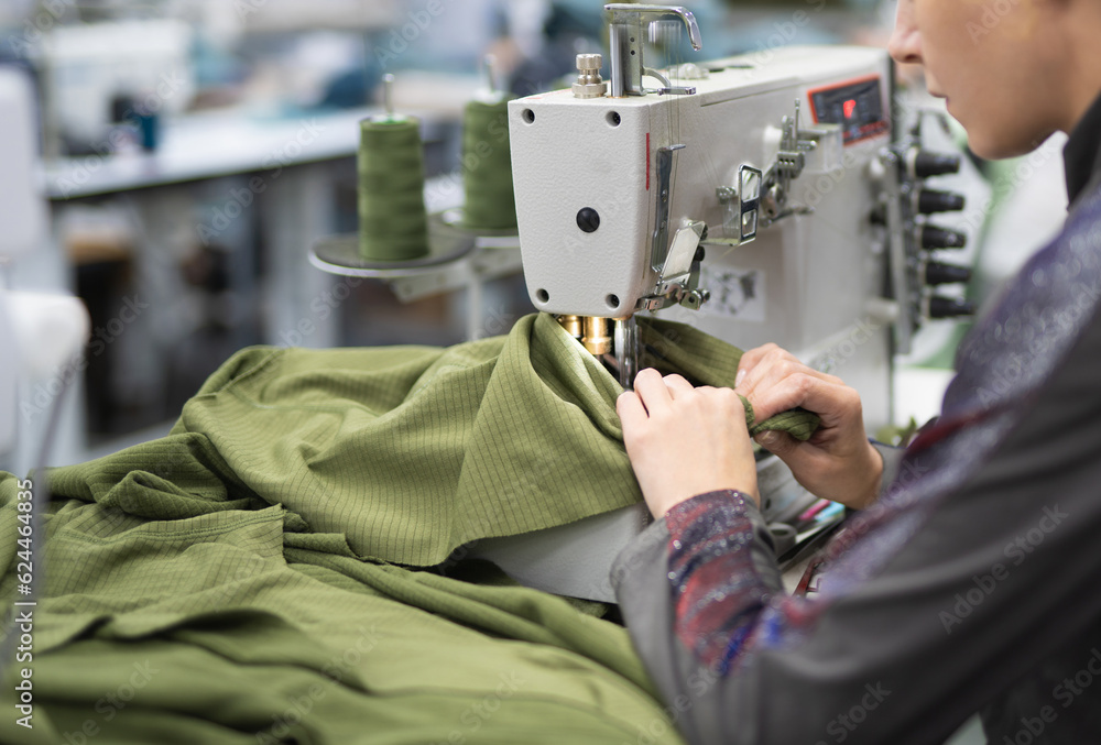 workers in an industrial garment factory sew clothes on sewing machine ...