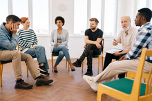 Wide Shot Of Mature Male Psychotherapist Leading Therapy Meeting With Addicted Diverse And Different Ages People Sitting In Circle During Therapy Meeting. Concept Of Consulting Mental Health Problem.