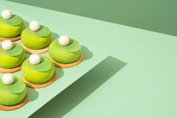 A platter of assorted green donut treats sits atop a wooden table