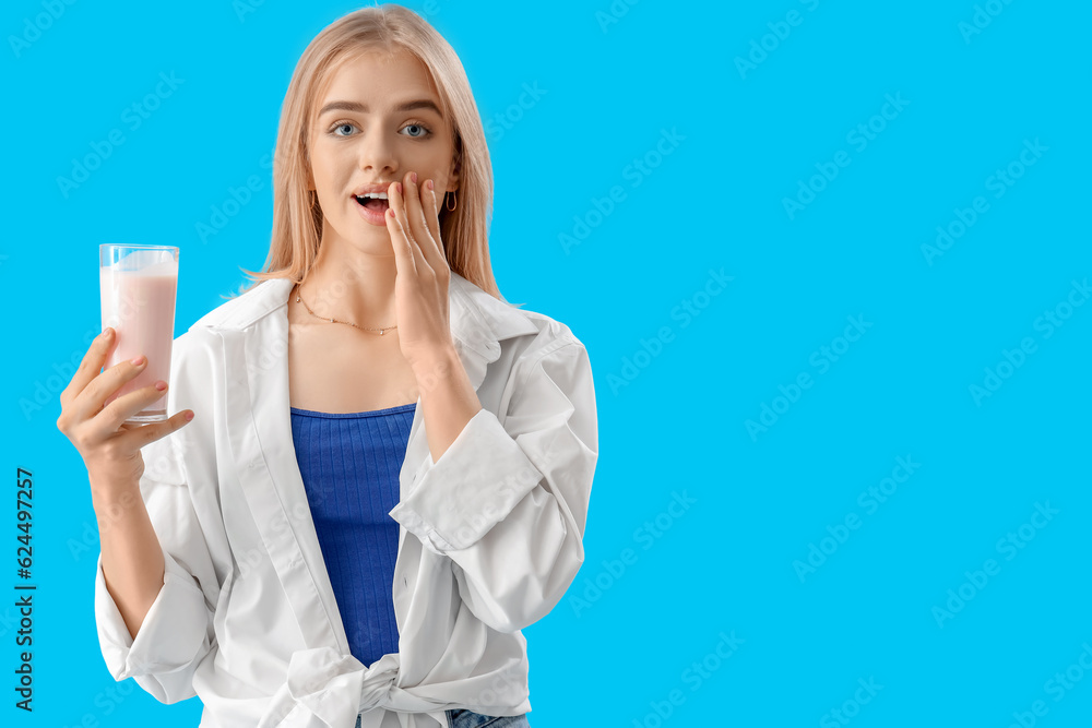 Surprised young woman with tasty yoghurt on blue background