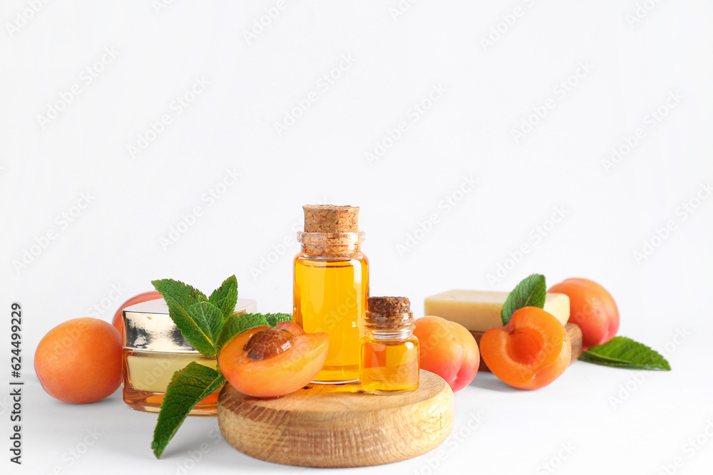 Composition with cosmetic products, ripe apricots and mint leaves on white background