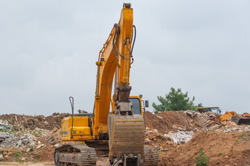 Wall Mural - Lonely excavator in a landfill with garbage and soils. The work of construction equipment in the production of earthworks