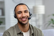 © Tetiana - Close-up photo. Portrait of a young hispanic man at home wearing a headset looking at the camera and smiling