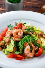 Wall Mural - Green salad of shrimp, mussels, cherry tomatoes oranges, grapefruits, capers, lettuce and arugula.