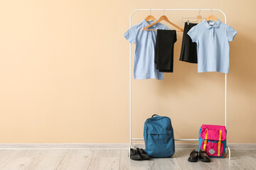 Wall Mural - Rack with stylish school uniform, backpacks and shoes near color wall