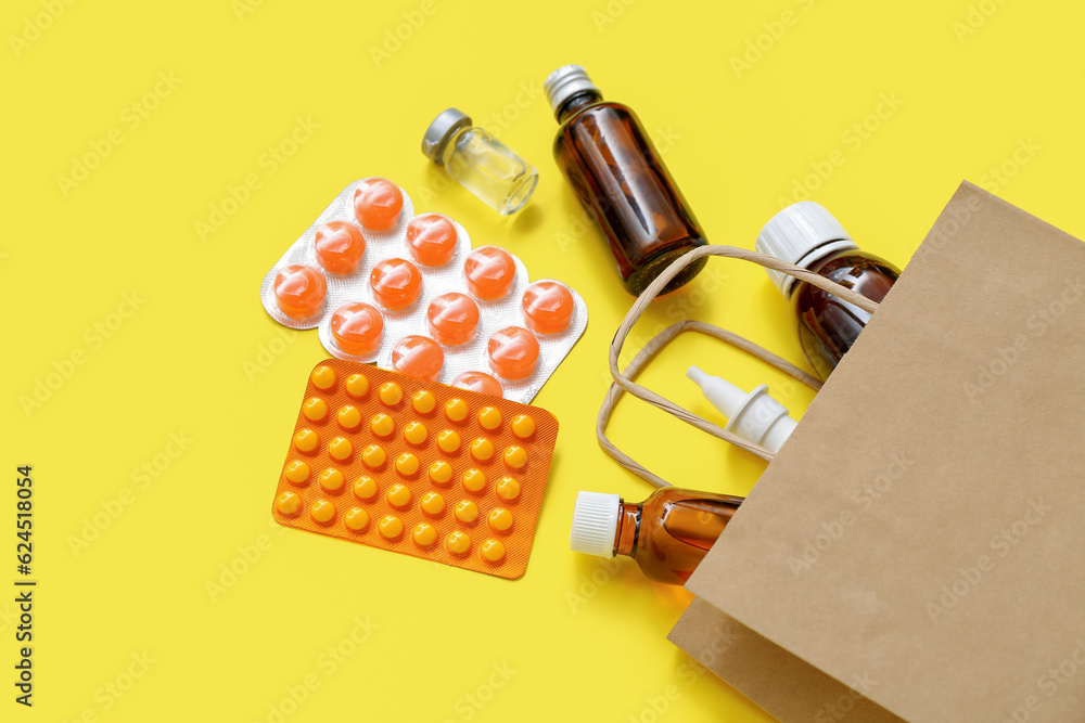 Shopping bag with different medicines on yellow background