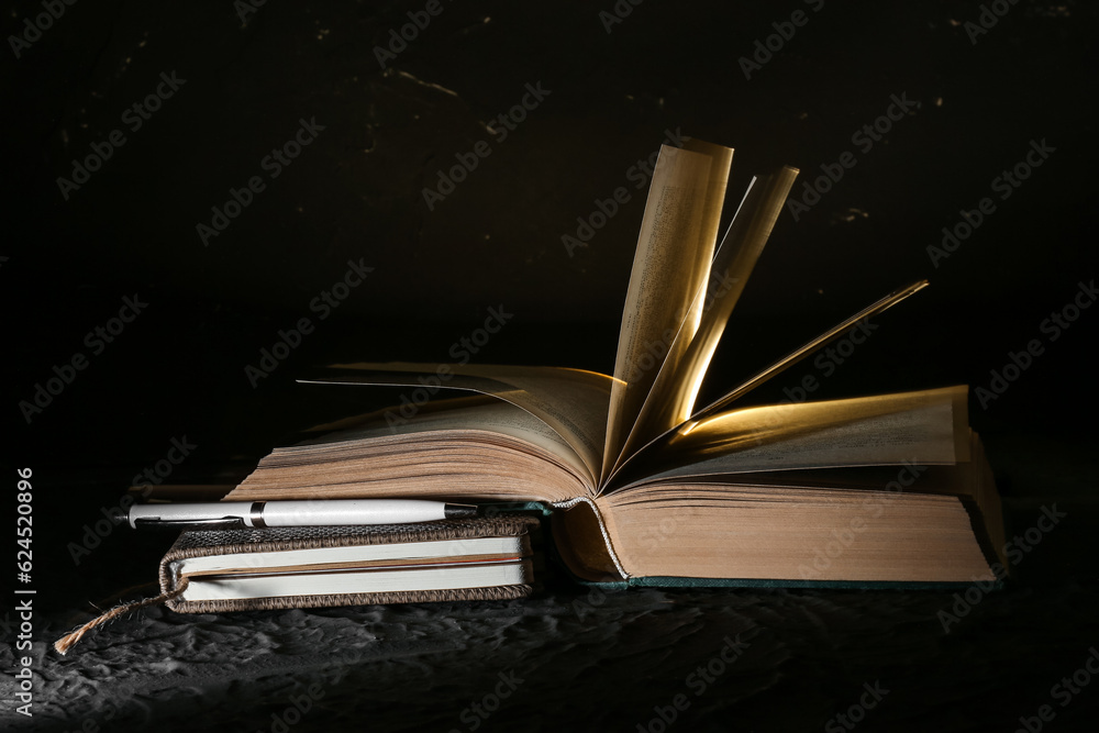 Book with glowing light on black background