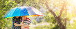Leinwandbild Motiv Boy and girl standing outdoors in rainy day under colourful umbrella.