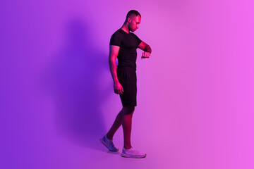 Wall Mural - Sporty African Man Walking Watching At Fitness Smartwatch, Purple Background