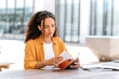 © Kateryna - Enthusiastic lovely trendy brazilian or hispanic young woman with curly hair, sitting on outside with a book in her hands, near the university campus, focused reading interesting book