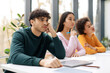 © Prostock-studio - Bored european student guy leaning on hand and listening lecture, sitting with classmates at table in classroom