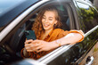© maxbelchenko - Happy woman in the car in the driver's seat looks at the smartphone. A young woman uses a mobile phone to navigate in the city, pay for parking. Business, technology concept.