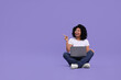 © New Africa - Happy young woman with laptop pointing at something on purple background. Space for text