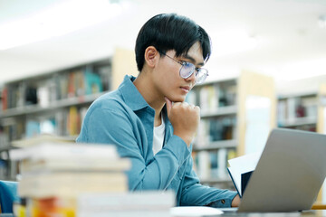 Poster - Young university student using laptop for online learning, searching and learning at library.