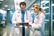 Male And Female Doctors Having Informal Meeting In Modern Hospital Looking At Digital Tablet. Generative AI