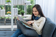 © Thirawatana - Young woman planning a trip and holding a map in the living room.