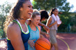 © wavebreak3 - Happy diverse female friends embracing and laughing with basketball at basketball court