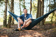 © baranq - Mid adult man enjoying summer trip sitting in hammock in forest