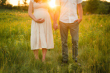 Couple Holding Hands In Meadow During Sunset & Holding Pregnant Belly