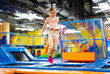 © Ievgen Skrypko - Pretty girl kid jumping on colorful trampoline at playground park and smiling. Caucasian preteen child during active entertaiments indoor
