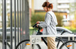 © Ievgen Skrypko - Cute laughing girl parking a bicycle on a bike parking near the supermarket. Eco-friendly urban transport.